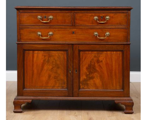 A mid 19th century mahogany cabinet with two short and one long drawer over twin panel cupboard doors, all standing on ogee b