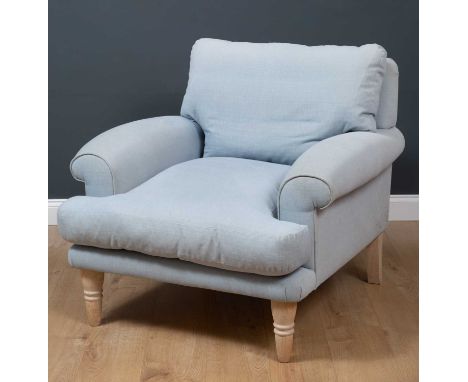 A deep light blue upholstered armchair originally acquired from Loaf, with turned tapering limed oak front legs, 98cm wide x 
