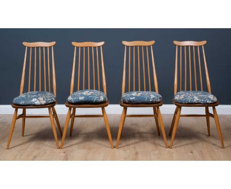 A set of four 1970's Ercol light elm and beech stick back dining chairs, on four outswept supports with loose floral seat cus