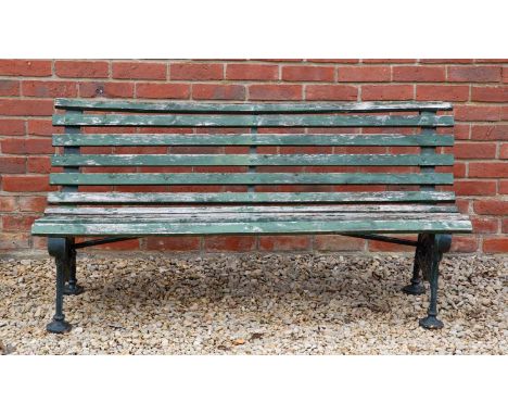 A green painted curved back wooden and cast iron garden bench, the bracket supports with scrolling decoration, 129cm wide x 5