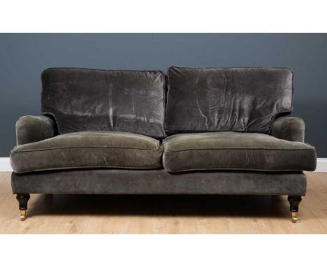 A contemporary grey upholstered sofa with turned tapering front legs terminating in brass casters, approximately 187cm wide x