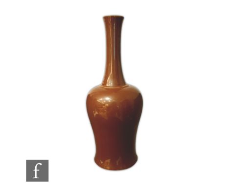 A Chinese iron-rust monochrome glazed bottle vase, the waisted vessel rising to a tapered shaft neck, Kangxi six-character (1