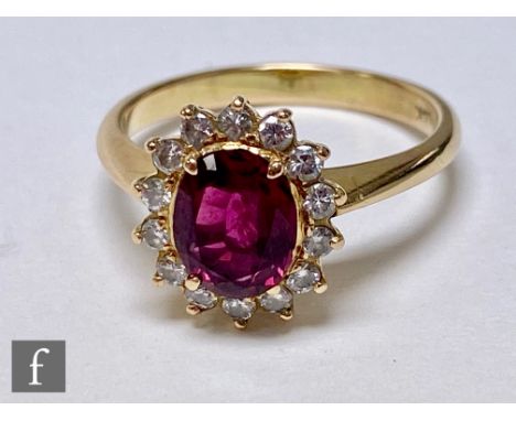 A 14ct ruby and diamond cluster ring, central oval ruby within a fourteen brilliant cut diamond surround, weight 4.3g, ring s