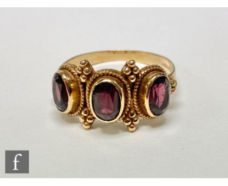 A 9ct hallmarked garnet three stone ring, collar set stones each within rope twist border, weight 3.5g, ring size R. 