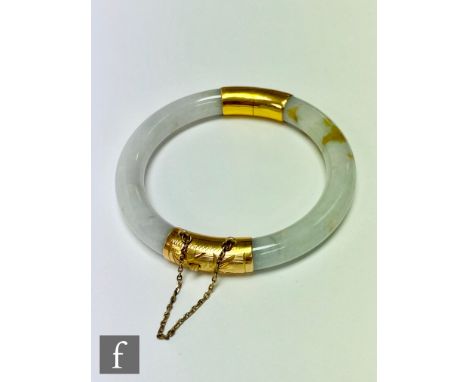 A 20th Century hinged jade bangle with gilt mounts, internal diameter 5cm. 