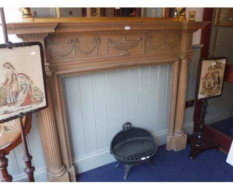 A GEORGE III STYLE PINE FIRE SURROUND, carved with swags and an urn with fluted columns, the shelf 167 cm long, 132 cm high 