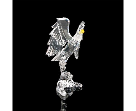 Faceted crystal figurine modeled as a bald eagle with yellow crystal beak and blue eyes. Eagle is perched with wings outstret