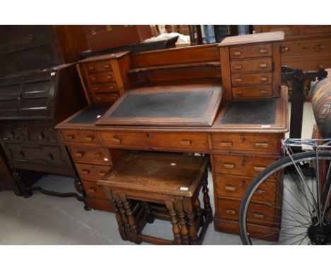 A late 19th or early 20th Century oak desk of interesting design with central writing slope and shelf back with stationery dr