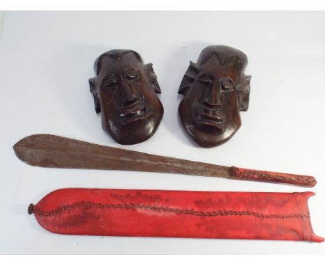 Leaf shaped African short sword in a red skin scabbard together with 2 well carved tribal wall masks (24cm high)