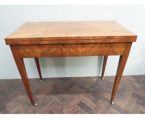19th century golden walnut fold over top card table on tapering legs to brass and ceramic casters 