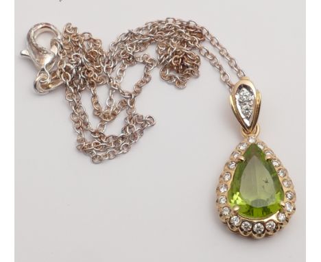 A peridot and diamond pendant, the central tear drop shaped peridot weighing 3 carats approximately, surrounded by diamond wi