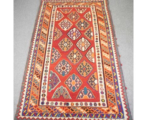 A Persian qashqai kilim, with all over lozenges, on a red ground, 290 x 175cmOverall there is no wear, but some light marks.