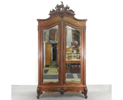 An early 20th century French walnut armoire, having a carved cresting, enclosed by a pair of mirrored doors142w x 45d x 272h 