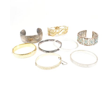 A collection of eight silver, rolled gold and costume bangles. The lot to include a sterling silver bangle with engraved zig 