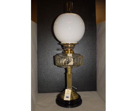 A Victorian brass oil lamp with opaque shade and clear glass reservoir, raised on reeded column.