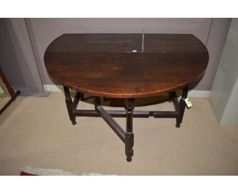 An 18th Century and later drop leaf dining table, the oval top above frieze drawer, raised on turned tapering legs, fitted ga