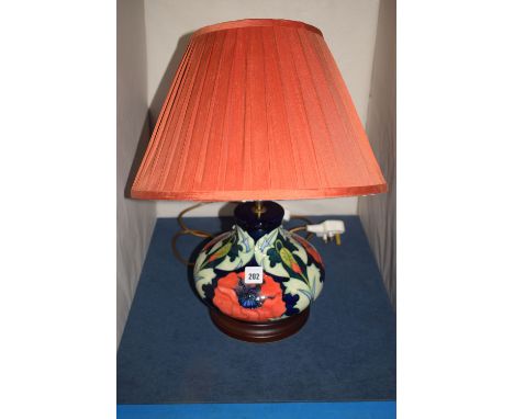 A modern Moorcroft ceramic lamp of globular form, decorated poppies on dark blue ground, complete with terracotta pleated sha