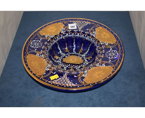 A hand blown blue tinted glass cabinet plate with white enamel and gilded hand-painted decoration in panels.