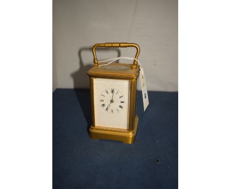 A late 19th Century brass carriage clock, roman dial, raised on square cutaway plinth base.