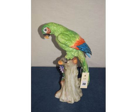 A ceramic parrot standing on a tree stump base (no maker's marks).