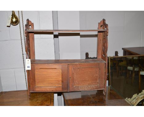 A stained wood hanging shelf unit, fitted a pair of panel doors to base, held by pierced sides.