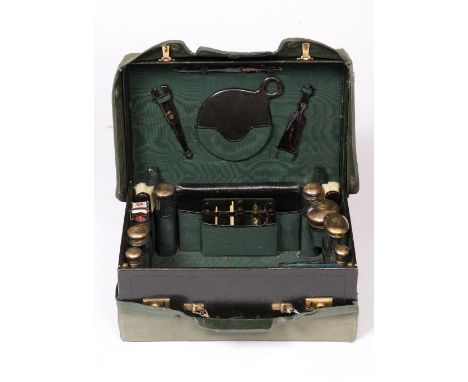 A GREEN LEATHER GENTLEMANS DRESSING CASE fitted with glass bottles with silver gilt lids, tortoiseshell glove stretcher, shoe