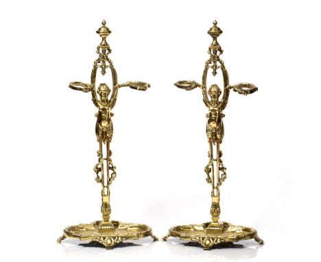 A PAIR OF VICTORIAN CAST BRASS FIRE IRON OR STICK STANDS of female figural form with scrolling supports and urn finials, 71cm