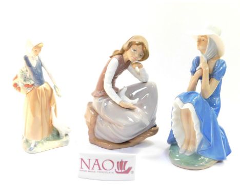 Three Nao porcelain figures, modelled as a seated girl wearing a bonnet, a girl with a goose and fruit, and a seated girl wit