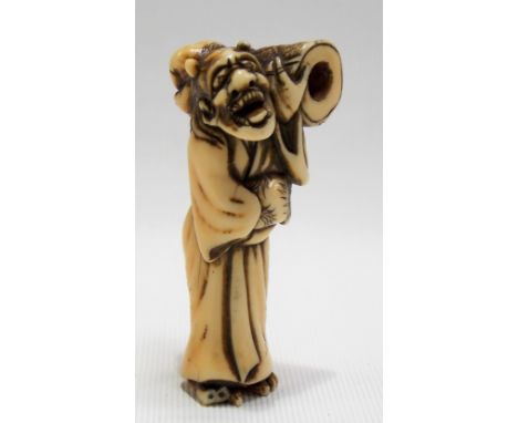 18th Century Japanese carved ivory netsuke modelled as a mythical figure with grotesque mask carrying a bundle, height 6cm