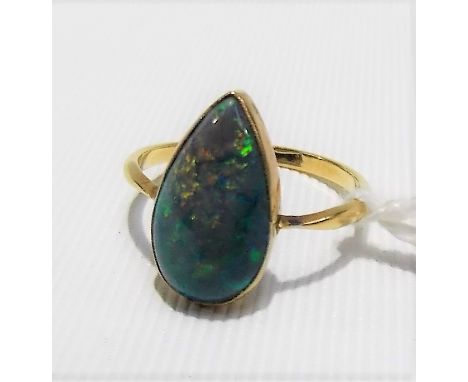 Yellow metal black NOT BOLDER opal set ring, the pear shaped polished stone displaying green, blue, orange and red and of 3ct