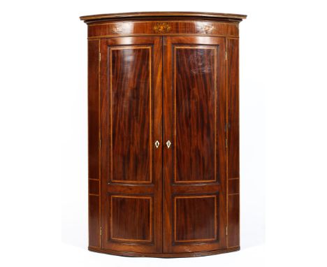 A 19th century veneered bow fronted corner cabinet, the frieze decorated with marquetry shells above two panelled doors featu