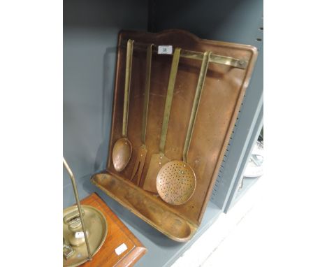 A set of vintage kitchen utensils with brass and copper fitments housed in rack