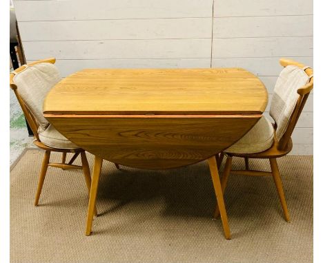 A blonde ercol table and two chairs 