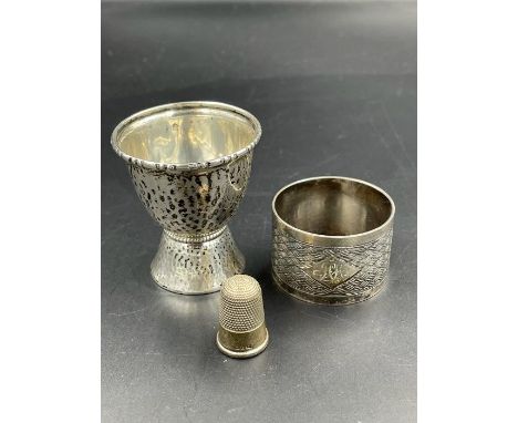 A silver egg cup, thimble and a napkin ring.