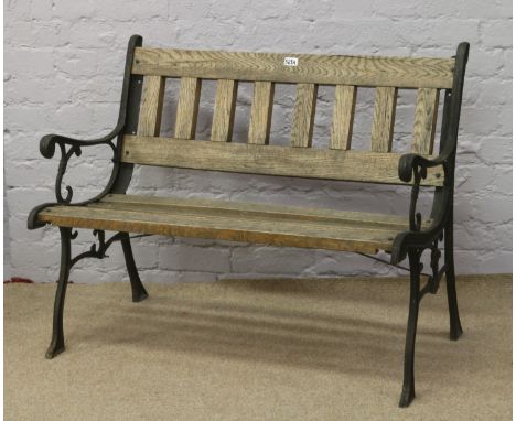 A cast iron two seat garden bench with oak slats.