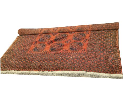 A large Middle Eastern wool carpet, rust ground with geometric pattern. Length 365 x Width 262cm. Four tiny pulls.