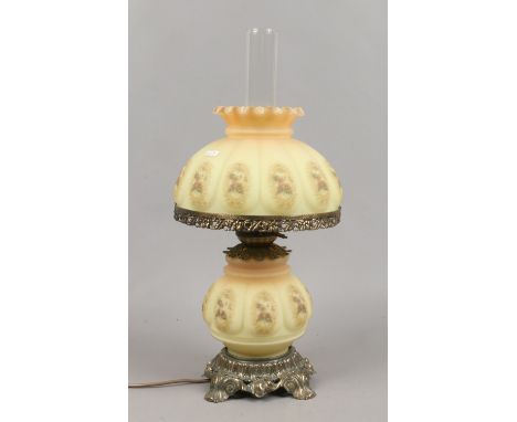 A tablelamp formed as an oil lamp with yellow glass shade and floral decoration.