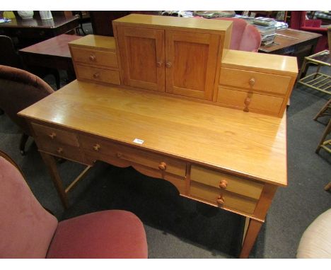 A bespoke light oak desk with raised back having a two door cupboard and nine drawers on square tapering leg supports, 121cm 