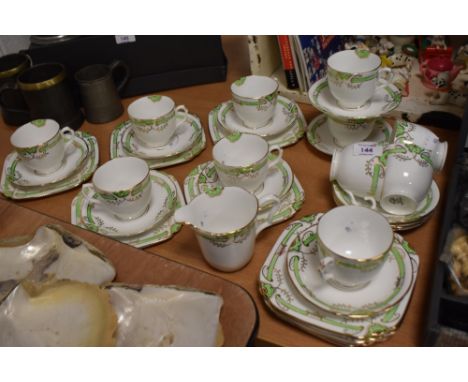 A collection of Longton china Art Deco cups and saucers, side plates and a jug, having green banding with gilt accents.