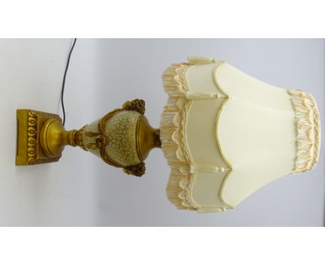 Classical style gilded baluster table lamp with cherub masks on moulded square base with fringed shade, H84cm overall 