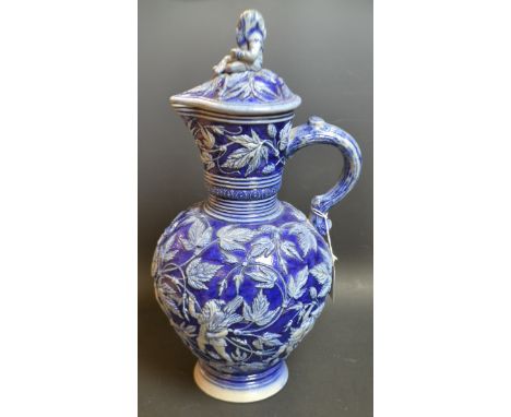A Westerwald salt glazed stoneware ale jug and cover, glazed in alternating tones of dark and light blue, applied in slip wit