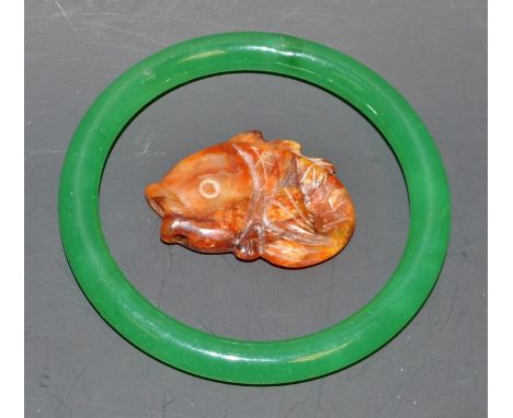 A stained green stone hoop bangle;  a carved stone fish (2)