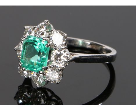 Columbian emerald and diamond set ring, the central Columbian emerald at 1.74 carats with a round cut diamond surround on whi