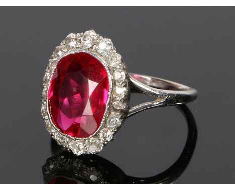 Diamond and simulated ruby ring, the simulated ruby held within a round cut diamond surround to white metal, ring size L