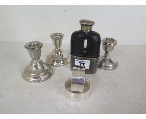 Three small weighted silver candlesticks, a pair of silver napkin rings and a hip flask with silver top and cup - damage to f