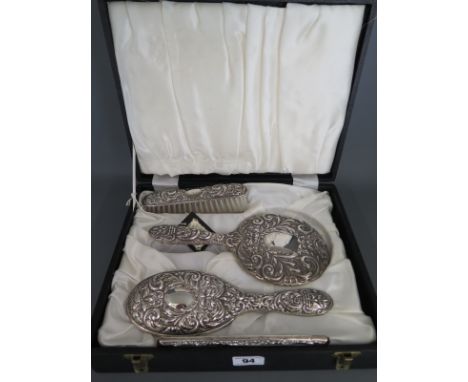 A silver four piece embossed dressing set - boxed, generally good, comb needs replacing
