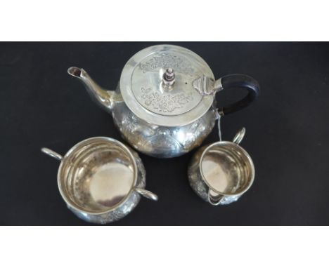 A silver hallmarked three piece tea service consisting of teapot, milk and sugar with foliate design engraving, central carto