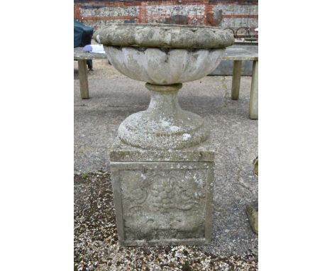 A Regency style weathered reconstituted stone garden urn planter standing on a square pedestal base