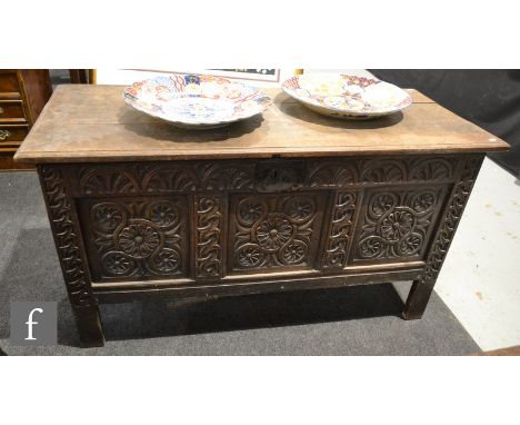 An 18th Century and later oak coffer chest, with a foliate and rosette carved frieze and triple fielded front panel over stil