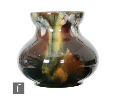 An early 20th Century Linthorpe pottery vase of squat baluster form, extending to a wide dish rim, the body with green, yello